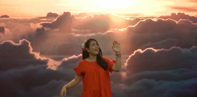 Cantautora: Massiel Rodríguez, cantando y con un fondo de un cielo con sol