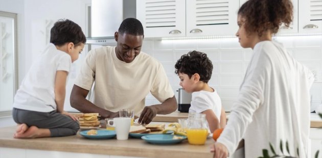 Una familia reunida al rededor de la mesa preparando los alimentos para consumir