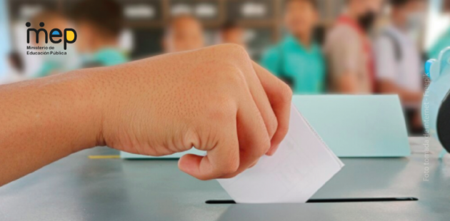 Mano de una persona estudiante votando en el aula