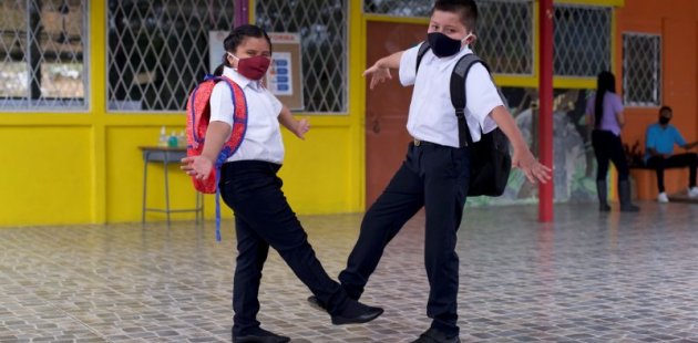 Niños se saludan con el pie en el centro educativo