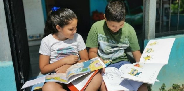 Dos niños con libros y dibujando. 
