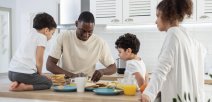 Una familia reunida al rededor de la mesa preparando los alimentos para consumir