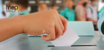 Mano de una persona estudiante votando en el aula