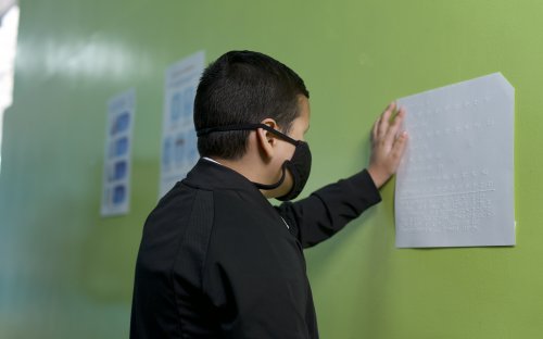 Fotografía de estudiante con discapacidad visual leyendo información en braille
