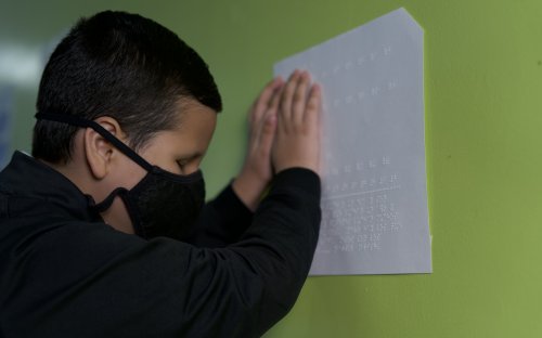 Fotografía de estudiante con discapacidad visual leyendo información en braille