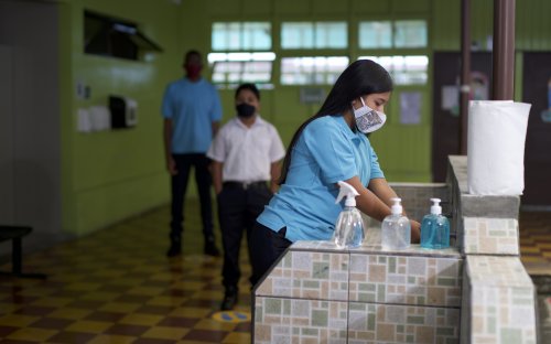 Tres estudiantes con mascarilla en el centro educativo haciendo fila 