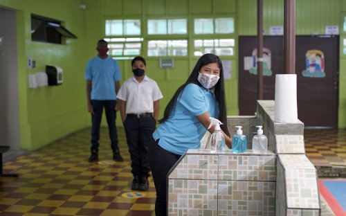 Tres estudiantes con mascarilla en el centro educativo haciendo fila