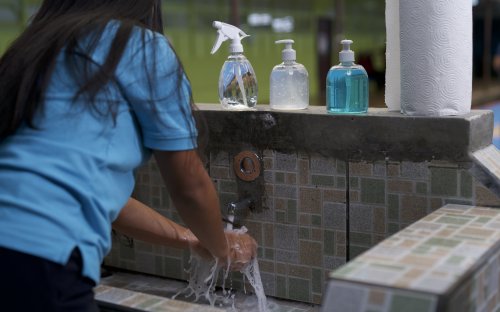 Estudiante lavándose las manos con agua y jabón