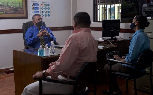 Familiares reunidos con el director en su oficina, distanciamiento y mascarillas