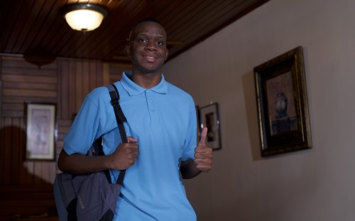 Estudiante de colegio en su casa, realizando una seña de aprobación 