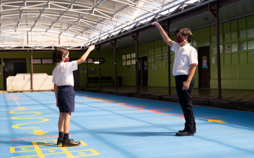 Estudiantes de primaria jugando, utilizan mascarilla, respetan el distanciamient