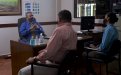 Familiares reunidos con el director en su oficina, distanciamiento y mascarillas