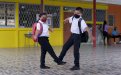 Dos estudiantes saludándose con el pie en el pasillo de un centro educativo